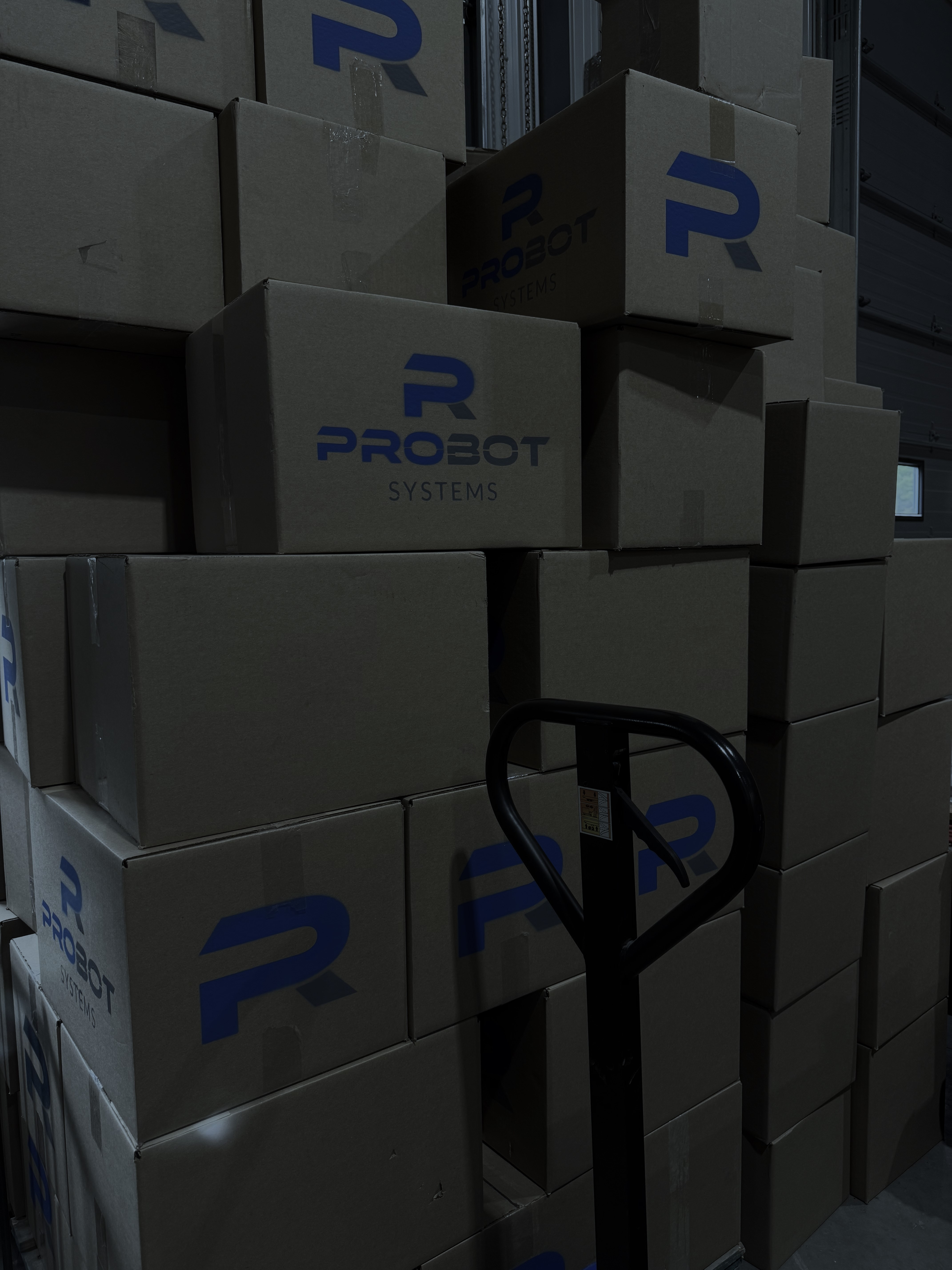 Pile de boîtes de carton Probot Systems et transpalette dans l’entrepôt