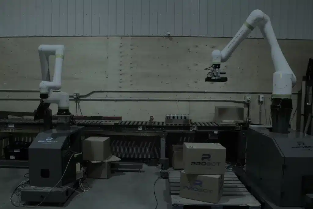 Deux robots collaboratifs manipulant des boîtes de carton sur des convoyeurs