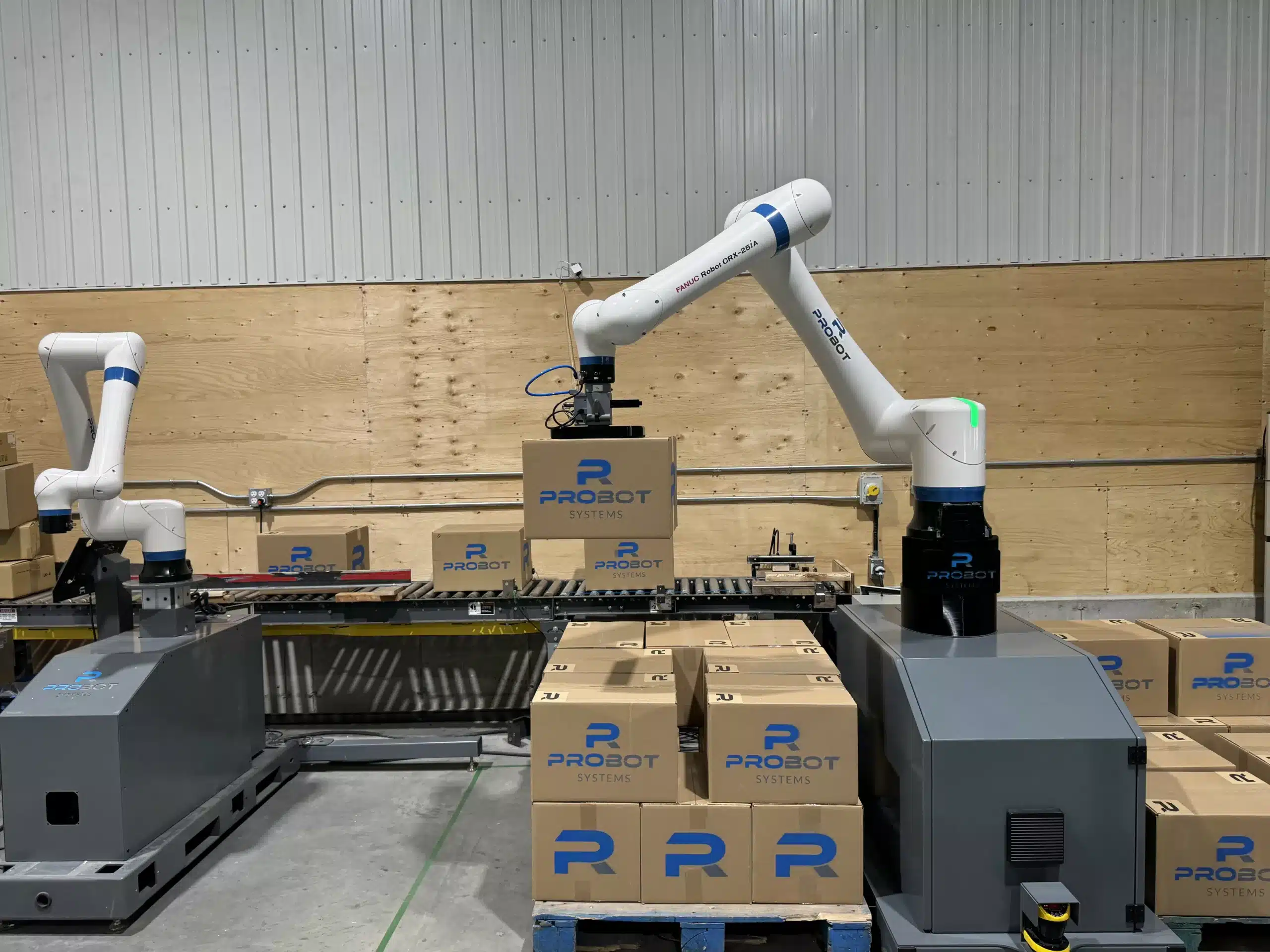 Deux robots collaboratifs palettisant des boîtes de carton au bout d’une ligne de convoyeurs
